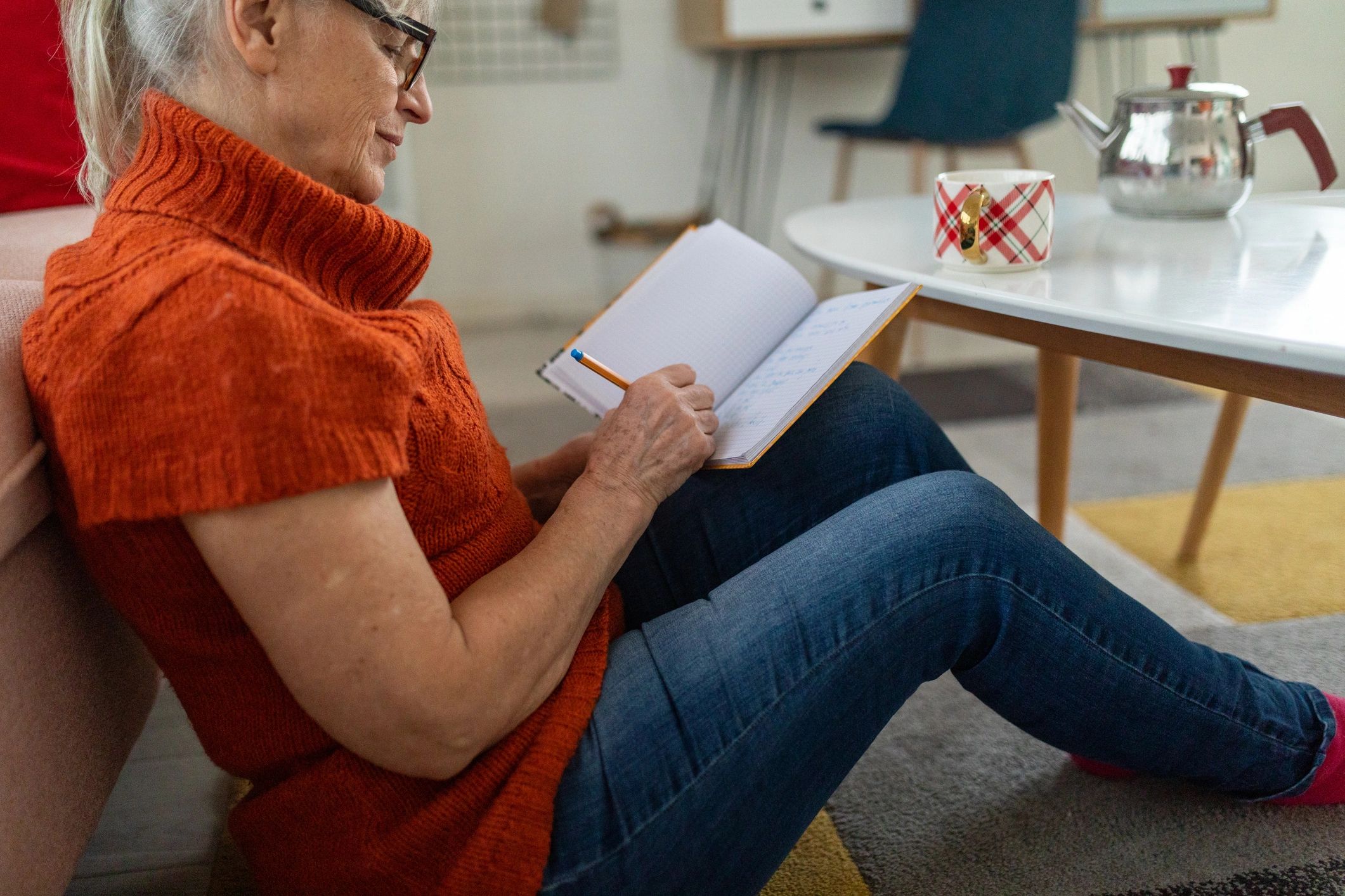 Senior woman writing in a notebook at home