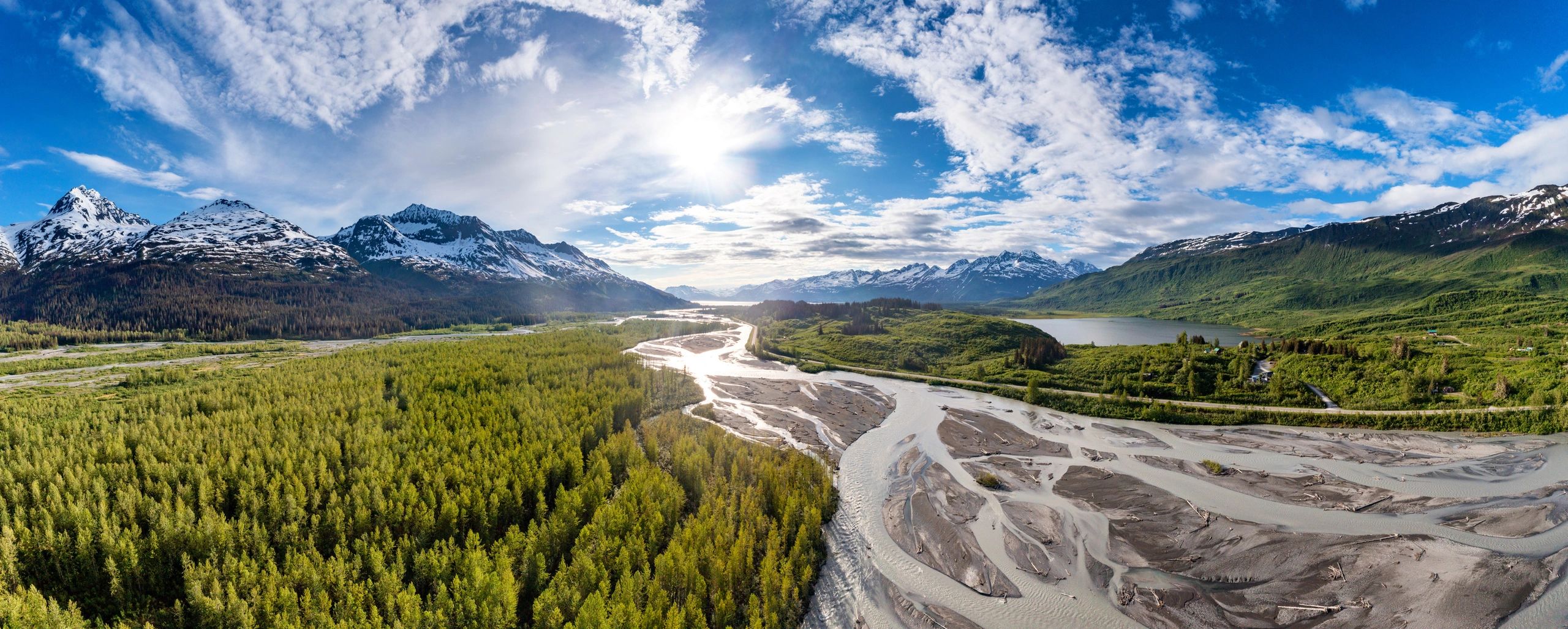 Aerial view of an Alaska road leading toward snow-capped mountains